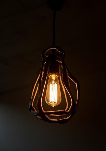 A unique pendant light fixture made from welded steel rings and an Edison bulb.